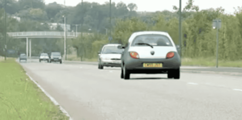 Car travelling along a British road in daylight.